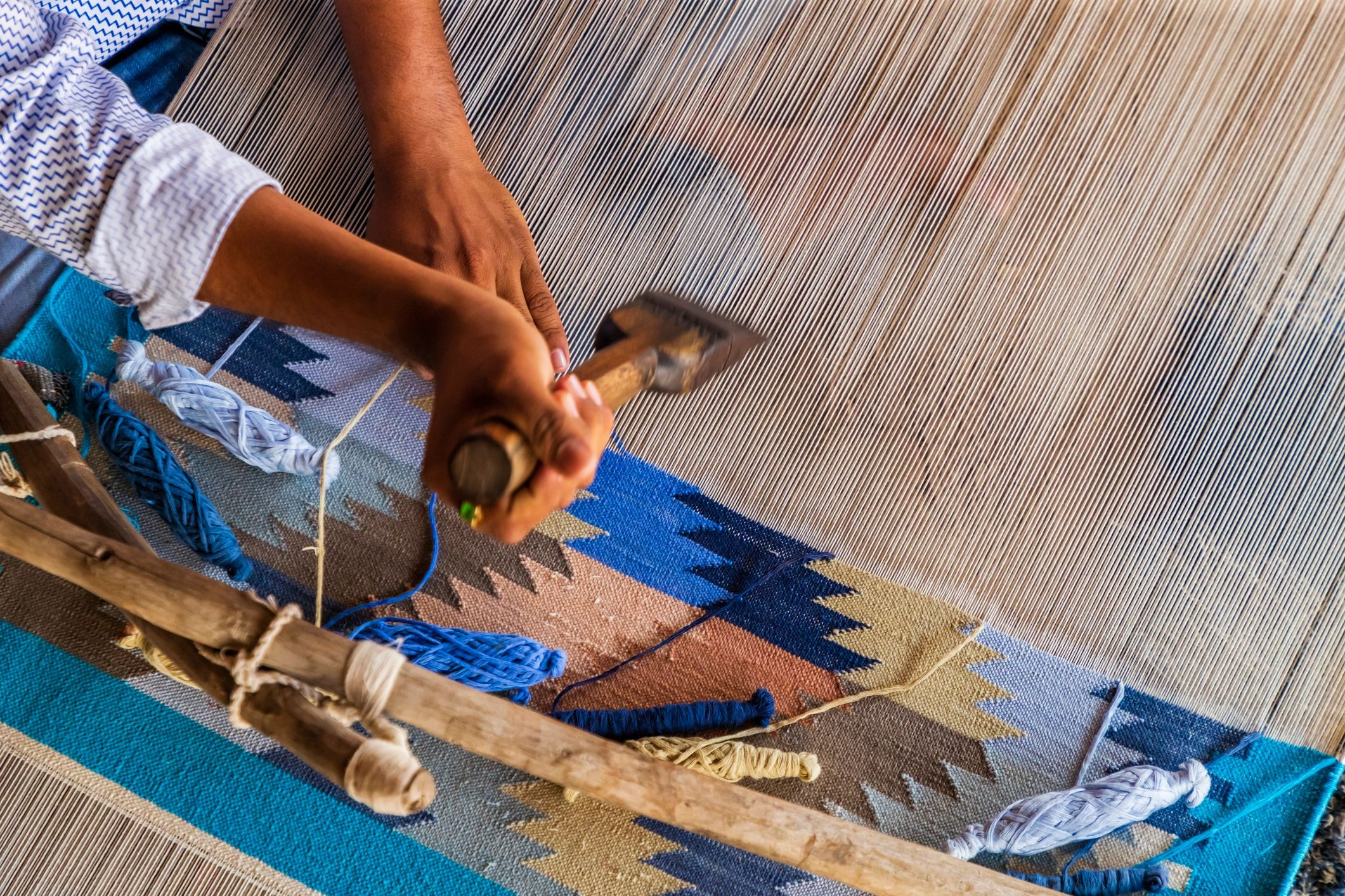 Artisan weaving a carpet on a traditional loom